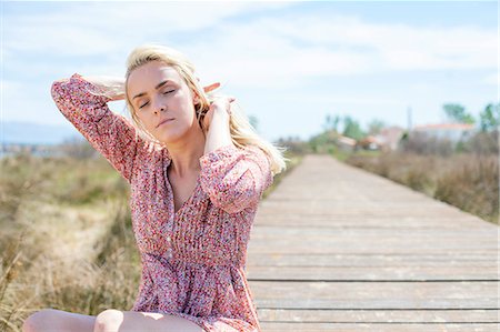 simsearch:6115-08239576,k - Young woman sitting on boardwalk eyes closed Stock Photo - Premium Royalty-Free, Code: 6115-08239567