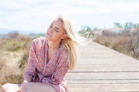 simsearch:6115-08239576,k - Young woman sitting on boardwalk eyes closed Stock Photo - Premium Royalty-Free, Code: 6115-08239566