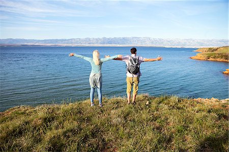 simsearch:6115-08239578,k - Young couple standing on cliff arms outstretched Stock Photo - Premium Royalty-Free, Code: 6115-08239594