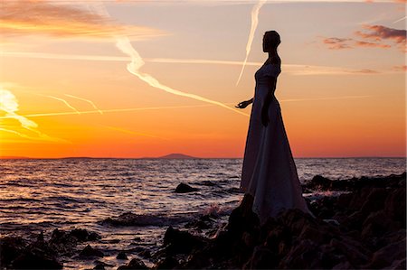 silhouettes of people thinking - Bride overlooking sea against sunset Stock Photo - Premium Royalty-Free, Code: 6115-08239501