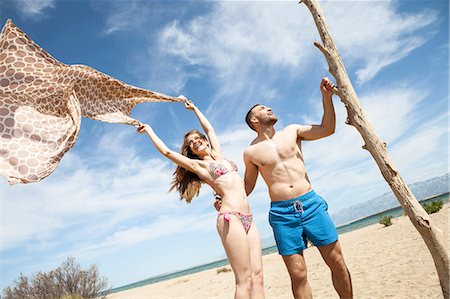 simsearch:6115-08239578,k - Happy young couple on beach fooling around Stock Photo - Premium Royalty-Free, Code: 6115-08239537