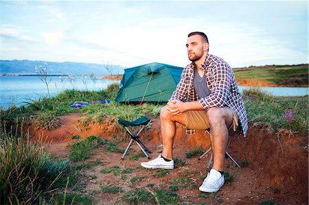simsearch:6115-08239576,k - Young man at campsite day dreaming Stock Photo - Premium Royalty-Free, Code: 6115-08239648