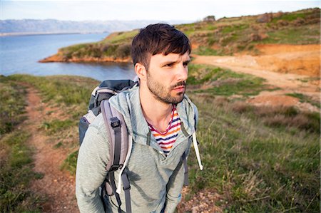 simsearch:6115-08239929,k - Young man hiking along coastal path Stock Photo - Premium Royalty-Free, Code: 6115-08239605