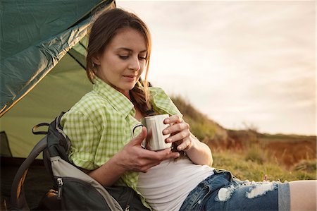 simsearch:6115-08239620,k - Young woman at campsite drinking cup of coffee Foto de stock - Sin royalties Premium, Código: 6115-08239624