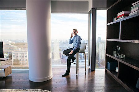 Businessman in apartment on the phone Stock Photo - Premium Royalty-Free, Code: 6115-08416148