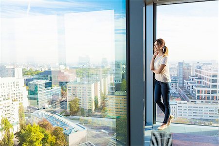 simsearch:6115-08416170,k - Woman in apartment looking through window Photographie de stock - Premium Libres de Droits, Code: 6115-08416167