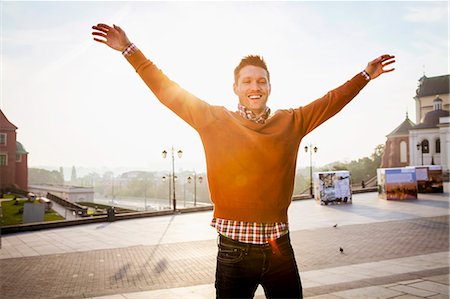 simsearch:6115-08416249,k - Mid adult man on a city break standing with arms raised Foto de stock - Sin royalties Premium, Código: 6115-08416242