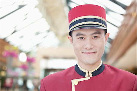 smiling chinese man with cap - Portrait of Bellhop, Close-Up Stock Photo - Premium Royalty-Free, Code: 6116-06938557