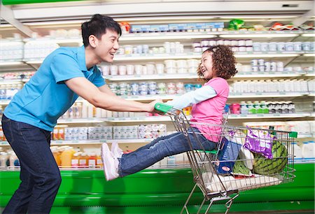 pushing - Father Pushing Daughter in Shopping Cart Inside Supermarket, Laughing Stock Photo - Premium Royalty-Free, Code: 6116-06938555
