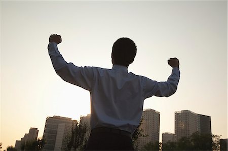 Young businessman with fists in the air celebrating, rear view Stock Photo - Premium Royalty-Free, Code: 6116-06938585