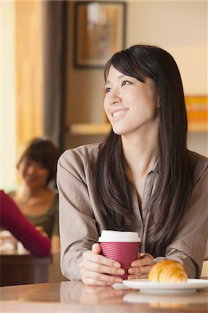 Beautiful young woman sitting at a coffee shop, looking away Stock Photo - Premium Royalty-Free, Code: 6116-06938606