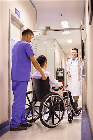 simsearch:694-03329116,k - Hospital Staff Pushing Patient In Wheelchair Foto de stock - Sin royalties Premium, Código: 6116-06938955