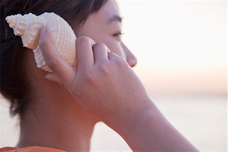 Teenage girl listening to seashell, close-up Photographie de stock - Premium Libres de Droits, Code: 6116-06939040