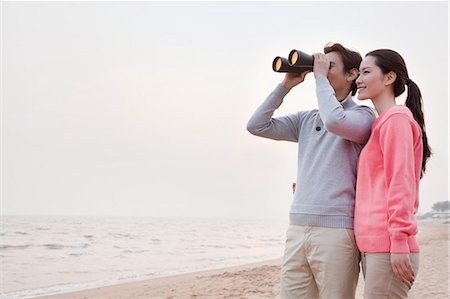 romantic beach sunset - Young Couple Looking at the Ocean with Binoculars Stock Photo - Premium Royalty-Free, Code: 6116-06939095