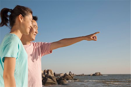 Father and Daughter pointing and looking to the sea Stock Photo - Premium Royalty-Free, Code: 6116-06939020