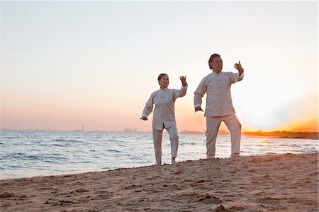 senior woman exercising by ocean - Two older people practicing Taijiquan on the beach at sunset, China Stock Photo - Premium Royalty-Free, Code: 6116-06939026