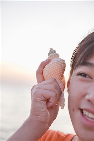 Teenage girl listening to seashell, close up Stock Photo - Premium Royalty-Free, Code: 6116-06939038