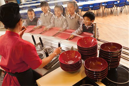 School cafeteria worker serves noodles to students Stock Photo - Premium Royalty-Free, Code: 6116-06939451