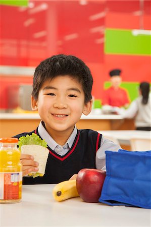 simsearch:6116-06939469,k - School boy portrait eating lunch in school cafeteria Foto de stock - Royalty Free Premium, Número: 6116-06939458