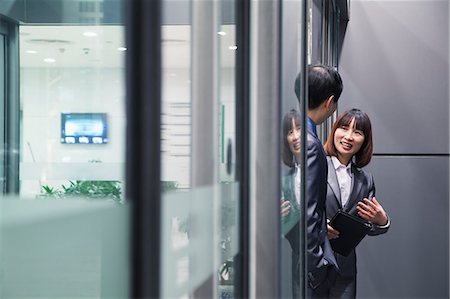 Business people talking together by a glass wall Stock Photo - Premium Royalty-Free, Code: 6116-06939437