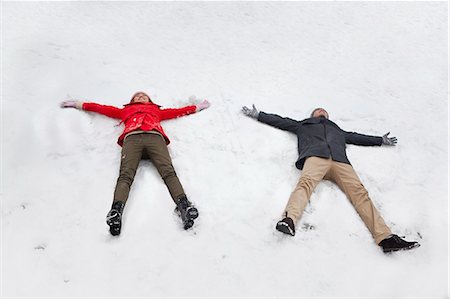 Young couple laying in snow making snow angels Stock Photo - Premium Royalty-Free, Code: 6116-06939543