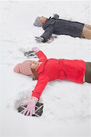 simsearch:6116-07086272,k - Young couple laying in snow making snow angels Stock Photo - Premium Royalty-Free, Code: 6116-06939544