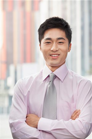 professional business man standing facing camera - Portrait of smiling young businessman Stock Photo - Premium Royalty-Free, Code: 6116-07084499