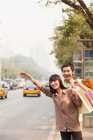 Young couple with shopping bags hailing a taxicab in Beijing Foto de stock - Sin royalties Premium, Código: 6116-07084516