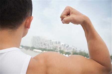 Rear view of young man flexing his bicep, tilt Stock Photo - Premium Royalty-Free, Code: 6116-07084600