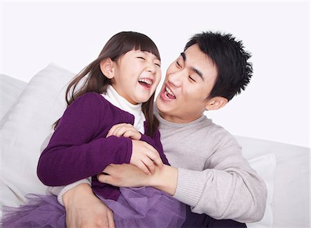 father children not grandparent asian - Father tickling daughter on the sofa, studio shot Stock Photo - Premium Royalty-Free, Code: 6116-07084709