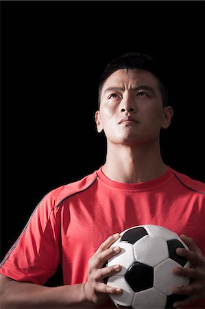 sportsman portrait - Footballer holding ball to chest, black background Stock Photo - Premium Royalty-Free, Code: 6116-07085153