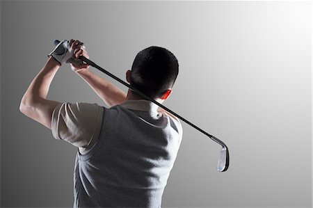 Young golf player swinging, rear view Stock Photo - Premium Royalty-Free, Code: 6116-07085171