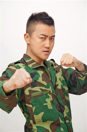 simsearch:6116-07084980,k - Portrait of man in military uniform putting up fists to fight Foto de stock - Sin royalties Premium, Código: 6116-07085210