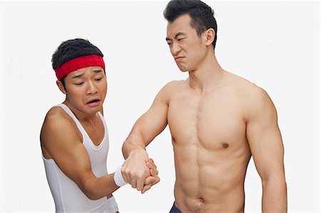 One young man beating another at arm wrestling, studio shot Stock Photo - Premium Royalty-Free, Code: 6116-07085224