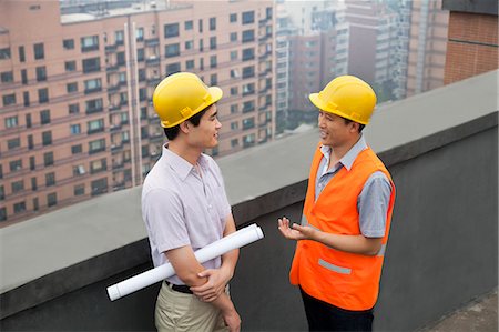 Architect And Construction Worker Talking On Rooftop Stock Photo - Premium Royalty-Free, Code: 6116-07085324