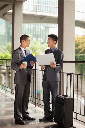 Two young businessmen working outdoor, looking at each other Stock Photo - Premium Royalty-Free, Code: 6116-07085492