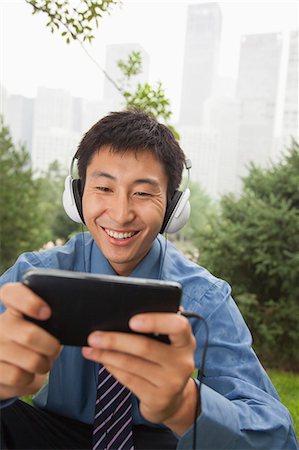 simsearch:6116-07085584,k - Young businessman listening to music on his MP4 player Foto de stock - Royalty Free Premium, Número: 6116-07085590