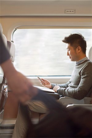 simsearch:6116-07085094,k - Young man sitting on a train using his phone Foto de stock - Sin royalties Premium, Código: 6116-07085899