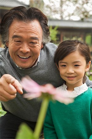 simsearch:694-03318999,k - Grandfather and granddaughter looking at flower in garden Fotografie stock - Premium Royalty-Free, Codice: 6116-07085994