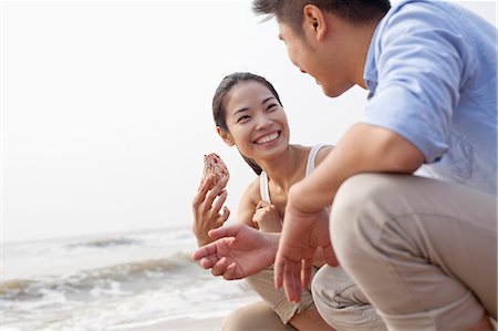 shell woman - Young couple looking at seashell at the waters edge, China Stock Photo - Premium Royalty-Free, Code: 6116-07085905