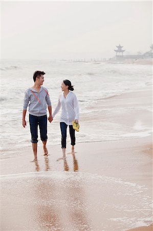 Young couple walking by the waters edge on the beach, China Foto de stock - Sin royalties Premium, Código: 6116-07085917