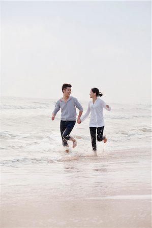 running to surf - Young couple holding hands running by the waters edge on the beach, China Foto de stock - Sin royalties Premium, Código: 6116-07085919