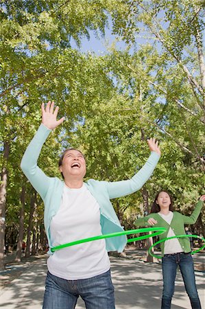 extended family - Granddaughter with grandmother playing with plastic hoop in the park Stock Photo - Premium Royalty-Free, Code: 6116-07085939