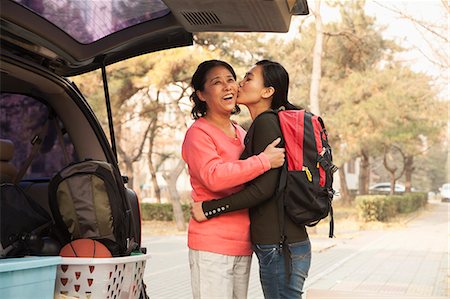 Mother and daughter embracing behind car on college campus Stock Photo - Premium Royalty-Free, Code: 6116-07086147