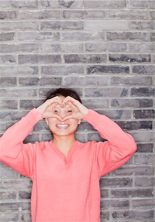 stand - Portrait of Young Woman Making Heart with Fingers Stock Photo - Premium Royalty-Free, Code: 6116-07086248