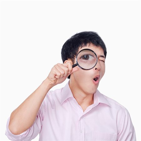 Young man looking through magnifying glass Photographie de stock - Premium Libres de Droits, Code: 6116-07086347