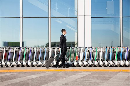 simsearch:649-07761008,k - Traveler with suitcase next to row of luggage carts at airport Photographie de stock - Premium Libres de Droits, Code: 6116-07086477