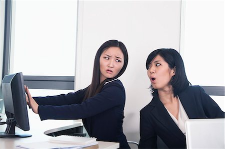 Officer worker hiding her computer from coworker Fotografie stock - Premium Royalty-Free, Codice: 6116-07086753