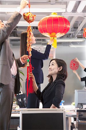 Coworkers hanging decorations in office for Chinese new year Stock Photo - Premium Royalty-Free, Code: 6116-07086766