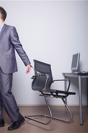 Businessman handcuffed to his office chair, walking away Fotografie stock - Premium Royalty-Free, Codice: 6116-07086737